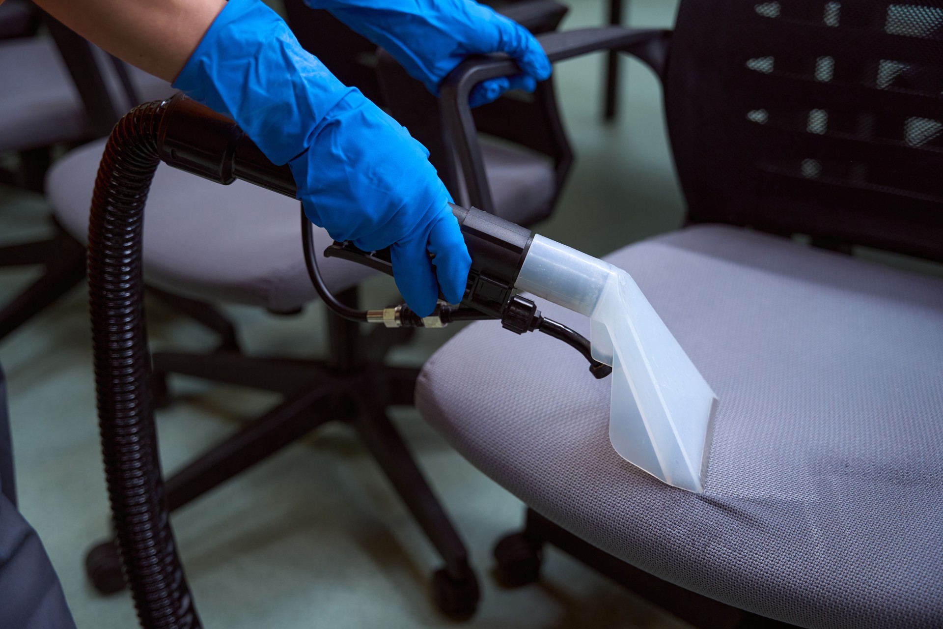 Professional janitor using speacila vacuum-cleaner on chairs